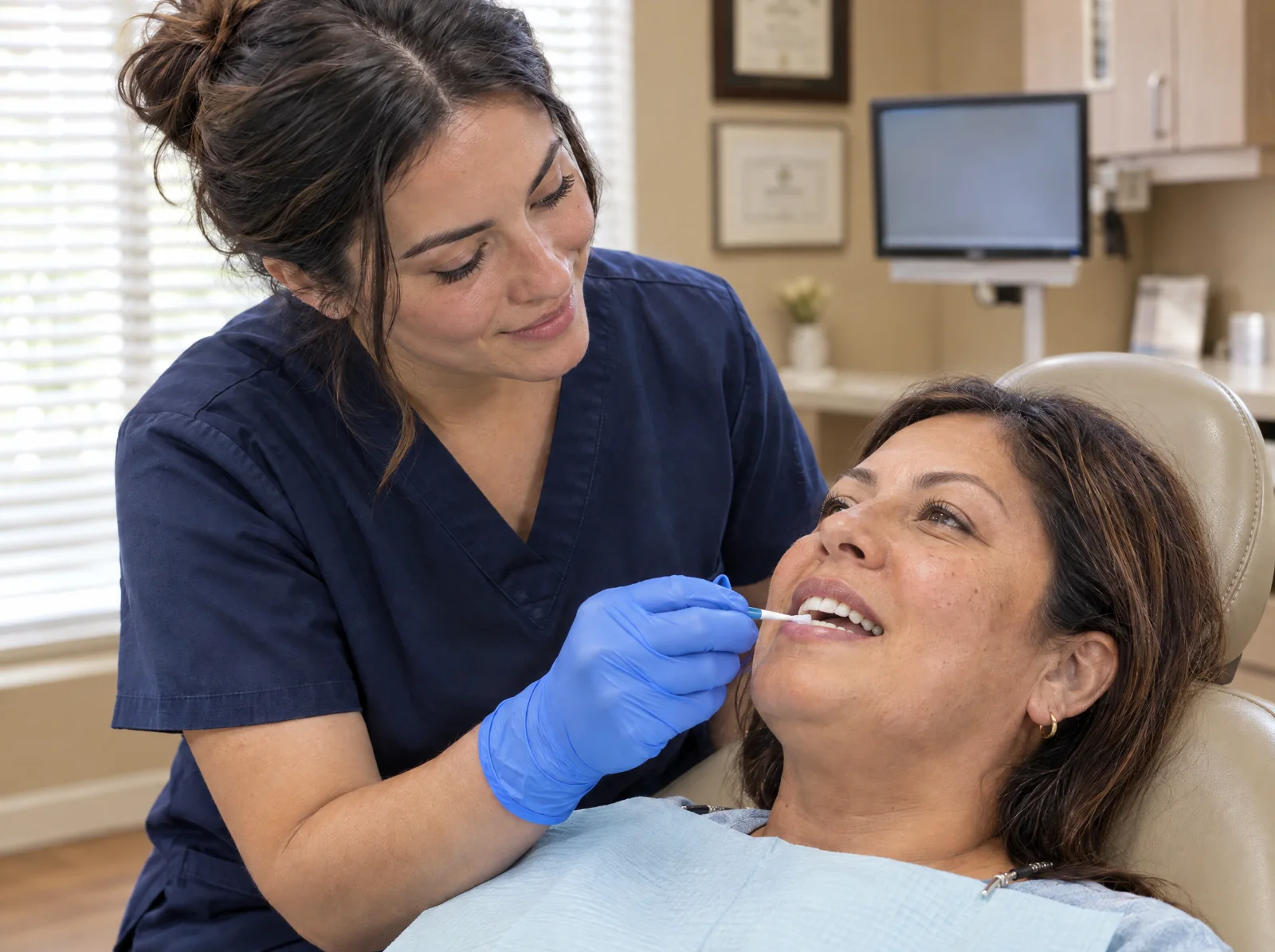 Dental hygienist brushing a fluoride treatment onto a patient’s front teeth in a treatment room